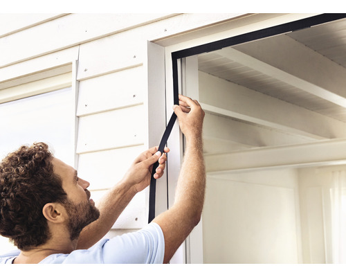 Bărbat aplicând o garnitură de etanșare la fereastră