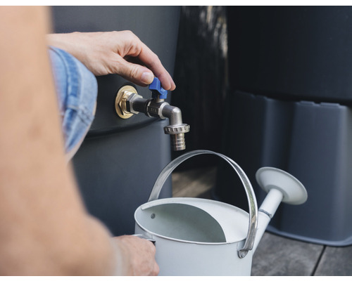 O persoană umple o stropitoare cu apă dintr-un rezervor de apă de ploaie.