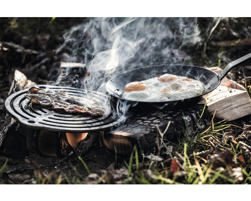 Bacon și ouă prăjite sunt preparate în aer liber pe foc deschis.