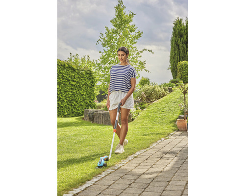 Femeie folosind un trimmer de margini de gazon în grădină