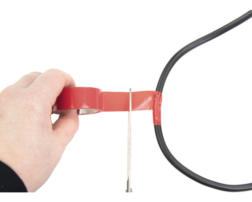 O persoană izolează un cablu de alimentare cu bandă izolatoare și foarfece.