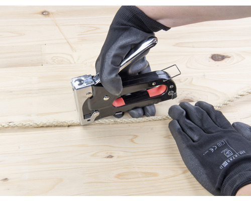 Persoană care fixează o frânghie cu un capsator pe lemn