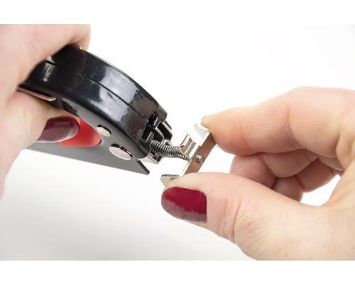 O persoană fixează o arcului pe o șină metalică cu un clește.