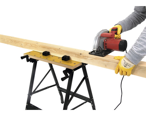 Muncitor taie o scândură de lemn pe un banc de lucru cu un ferăstrău circular.