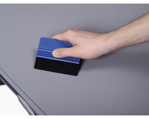 Mână folosește racletă pentru a netezi o suprafață