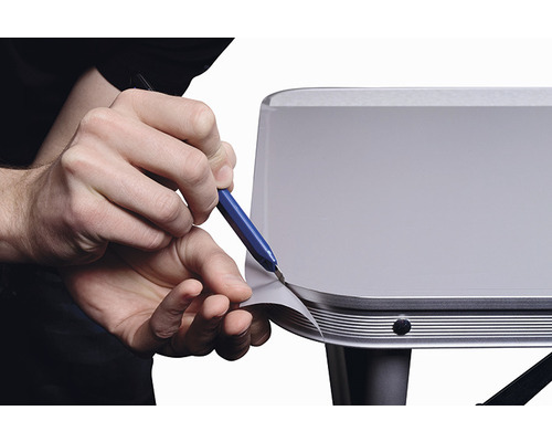 O persoană taie folie pe o suprafață cu un cuțit.