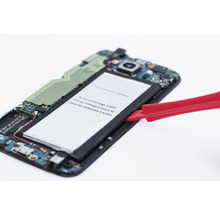 Smartphone deschis cu bateria scoasă și unealtă roșie