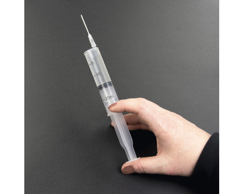 O mână ține o seringă de 20 de mililitri cu ac.