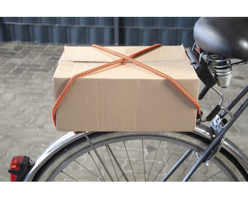 O cutie de carton este fixată pe o bicicletă cu un elastic de bagaje.