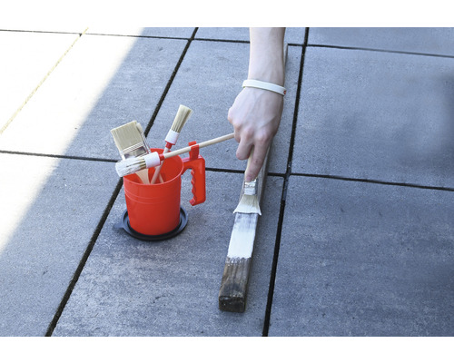 Găleată de vopsea cu diverse pensule și vopsirea unei bucăți de lemn