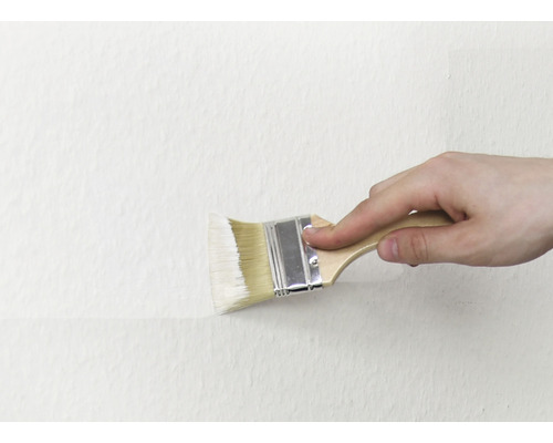 O persoană vopsește un perete cu o pensulă.