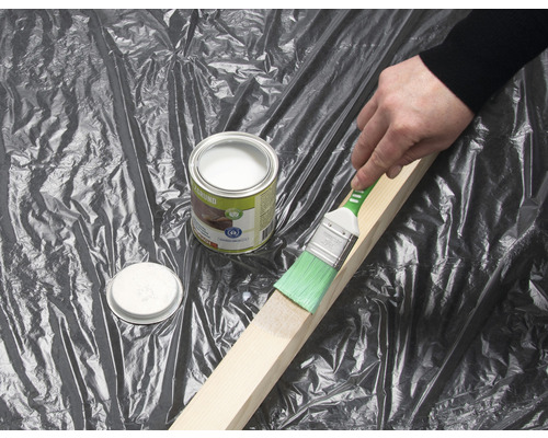 Vopsirea unei bucăți de lemn cu o pensulă și o cutie cu grund pentru lemn.