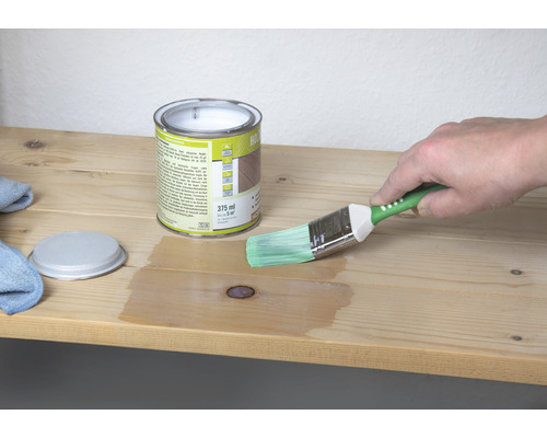 Cutie lazură pentru lemn cu pensulă în timpul aplicării pe o scândură de lemn