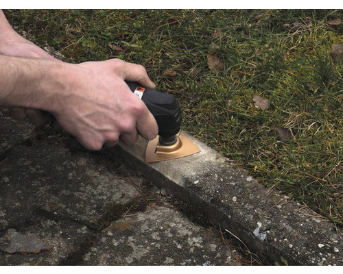 O persoană folosește un instrument multifuncțional pe o suprafață de beton în aer liber.