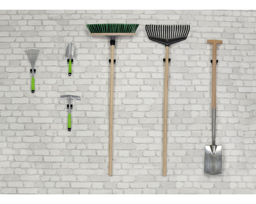 Unelte de grădinărit, cum ar fi mătura, grebla, lopata și sapa, atârnă pe un perete