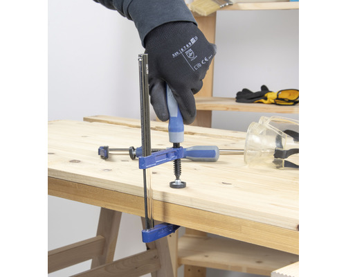 Un clește de strângere fixează două bucăți de lemn pe un banc de lucru.