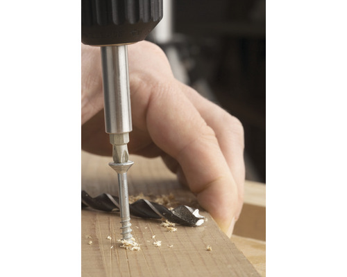 Un șurub este înșurubat într-o bucată de lemn cu o șurubelniță.