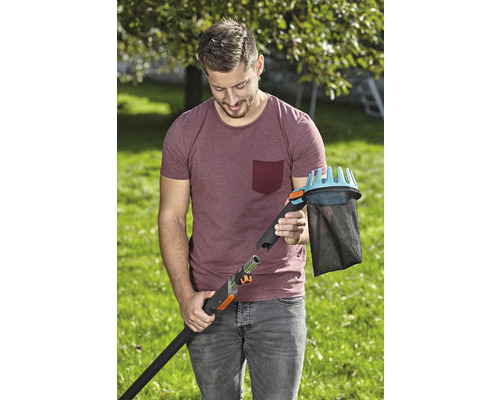 Un bărbat conectează un culegător de fructe la un mâner telescopic în grădină.