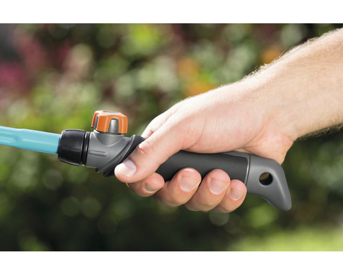 O mână ține un furtun de grădină cu ventil de închidere.