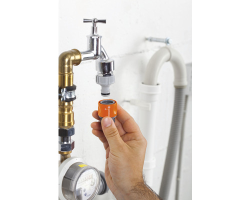 Mână atașează adaptorul Gardena la robinetul de apă pentru irigarea grădinii