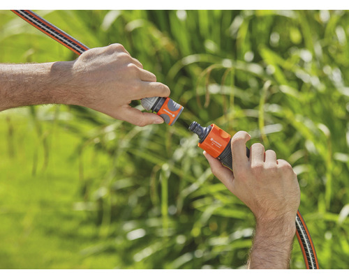 Două mâini conectează un furtun de grădină cu un conector de furtun.