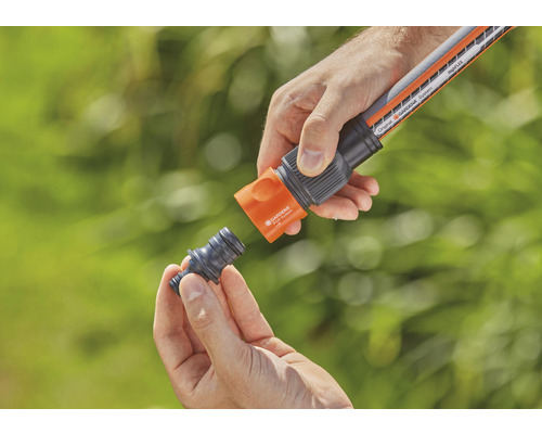 Persoană conectând furtun de grădină cu racord de furtun