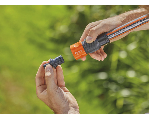 O persoană conectează o bucată de furtun de grădină la un furtun de grădină