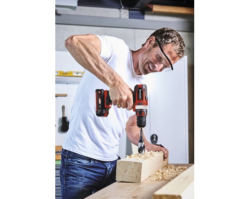 Un bărbat găurește o bucată de lemn cu o șurubelniță electrică fără fir.