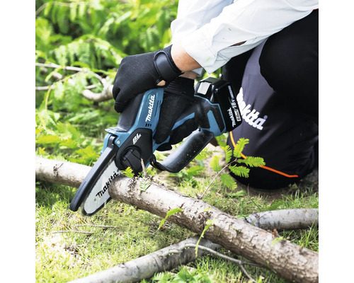 Fierăstrău de grădină cu acumulator Makita în uz, tăind o creangă.