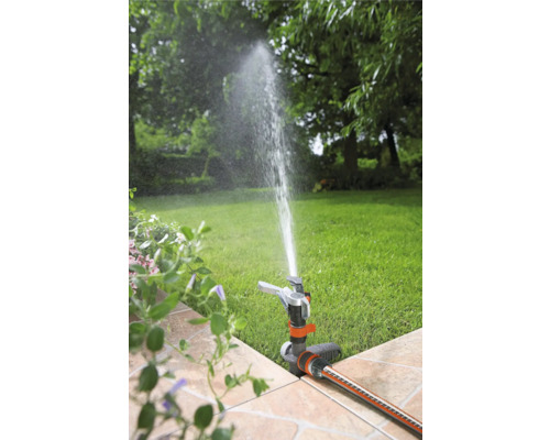 Scenă de grădină cu aspersor de gazon care udă gazonul
