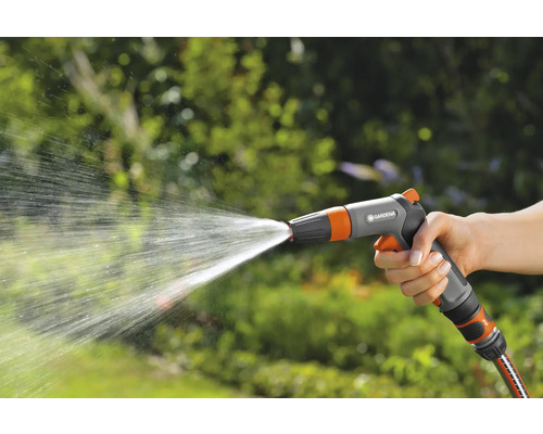 O mână ține un pistol de stropit din care țâșnește apă.