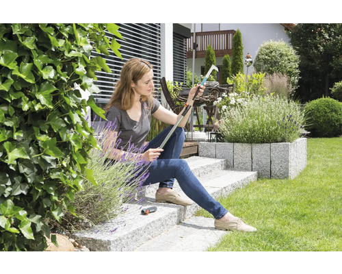 Femeie stând în grădină și inspectând un culegător de fructe