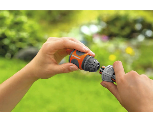 O persoană conectează două piese de furtun Gardena.