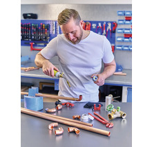 Un bărbat sudează țevi de cupru cu un arzător cu gaz într-un atelier.