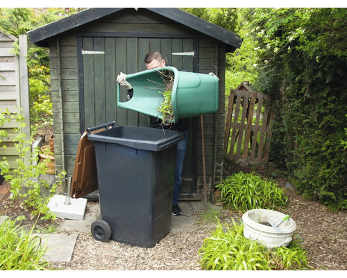 Bărbat care varsă deșeuri verzi într-un tomberon în grădină