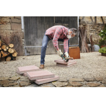 Artizan taie pietre de pavaj cu un polizor unghiular în aer liber.