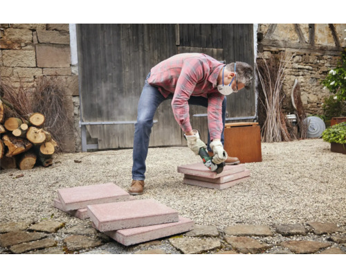 Artizan taie pietre de pavaj cu un polizor unghiular în aer liber.