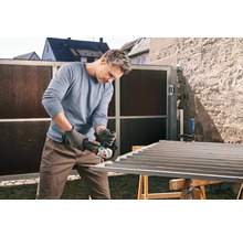 Bărbat șlefuind o poartă metalică cu un polizor unghiular în aer liber.