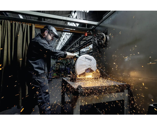 Un bărbat cu vizieră de protecție manevrează un ferăstrău circular Metabo, de unde zboară scântei.