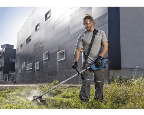 Bărbat taie iarba cu o mașină de tuns iarba cu acumulator în grădină