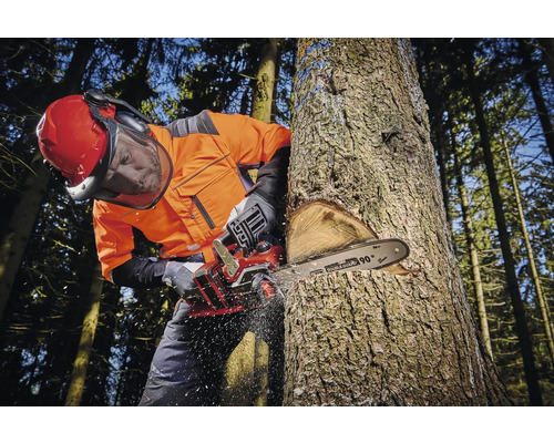 Bărbat cu îmbrăcăminte de protecție taie un copac cu un fierăstrău cu lanț