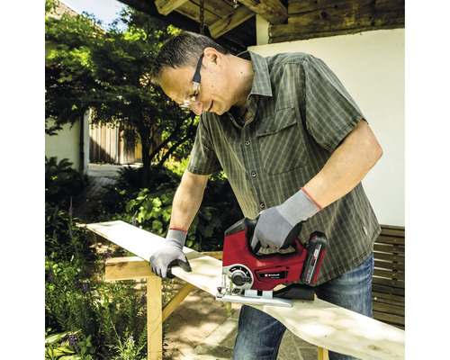 Bărbat taie o scândură de lemn cu un fierăstrău vertical în grădină