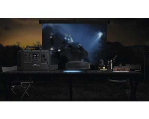 Scenă în aer liber cu stație de alimentare Bluetti, proiector și ecran pe o masă