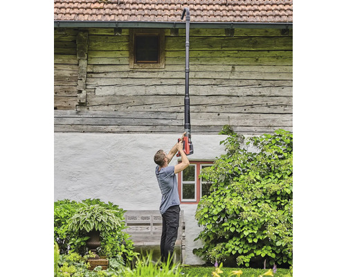 O persoană curăță o jgheabă cu un curățător de jgheaburi.