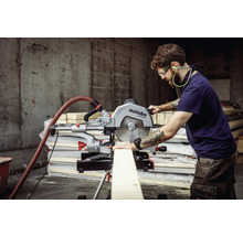 Un bărbat folosește un ferăstrău circular Metabo pentru a tăia o scândură de lemn. Se poartă echipament individual de protecție.