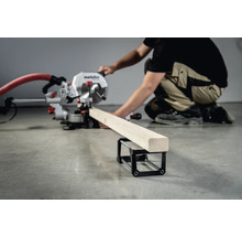 Un ferăstrău circular Metabo taie o scândură de lemn care se află pe un suport pentru piese de prelucrat.