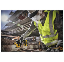 Un meșter cu ochelari de protecție și vestă de avertizare taie o bucată de metal cu o mașină de șlefuit DeWalt.