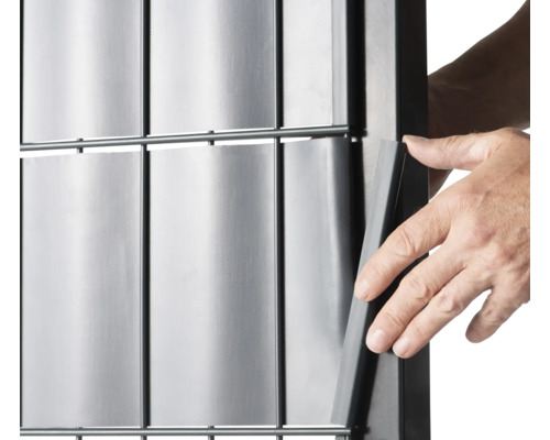 Prim-plan cu o persoană care introduce o fâșie de confidențialitate într-un gard.