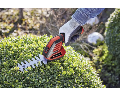 Foarfecă de tuns gard viu cu acumulator Einhell în uz pe un gard viu