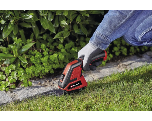 Sigla Einhell. O persoană folosește un foarfece de tuns iarba fără fir pentru a tunde marginile gazonului.